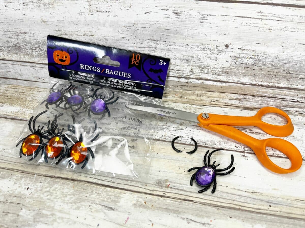 A package of halloween spiders and scissors on a table.