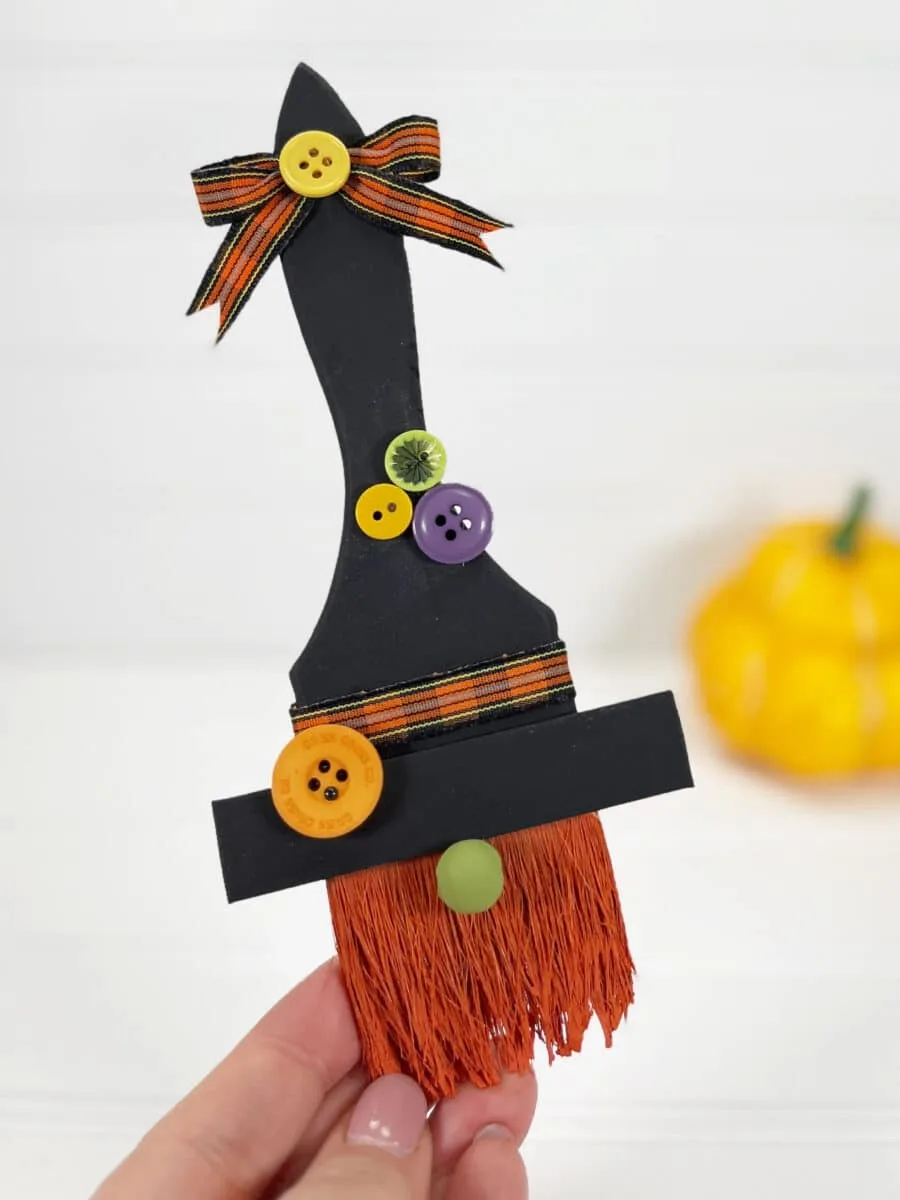 A person holding a witch hat with buttons.