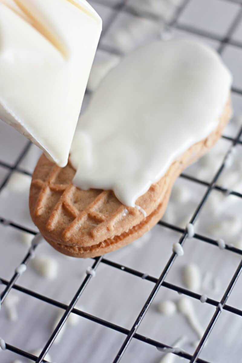 A person is frosting ghost cookies.