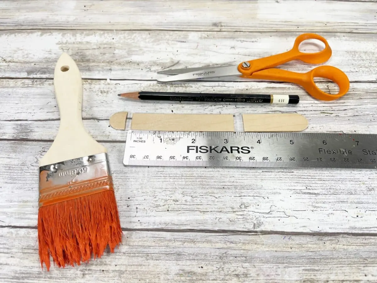 A ruler, paint brush, scissors and a ruler on a wooden table.