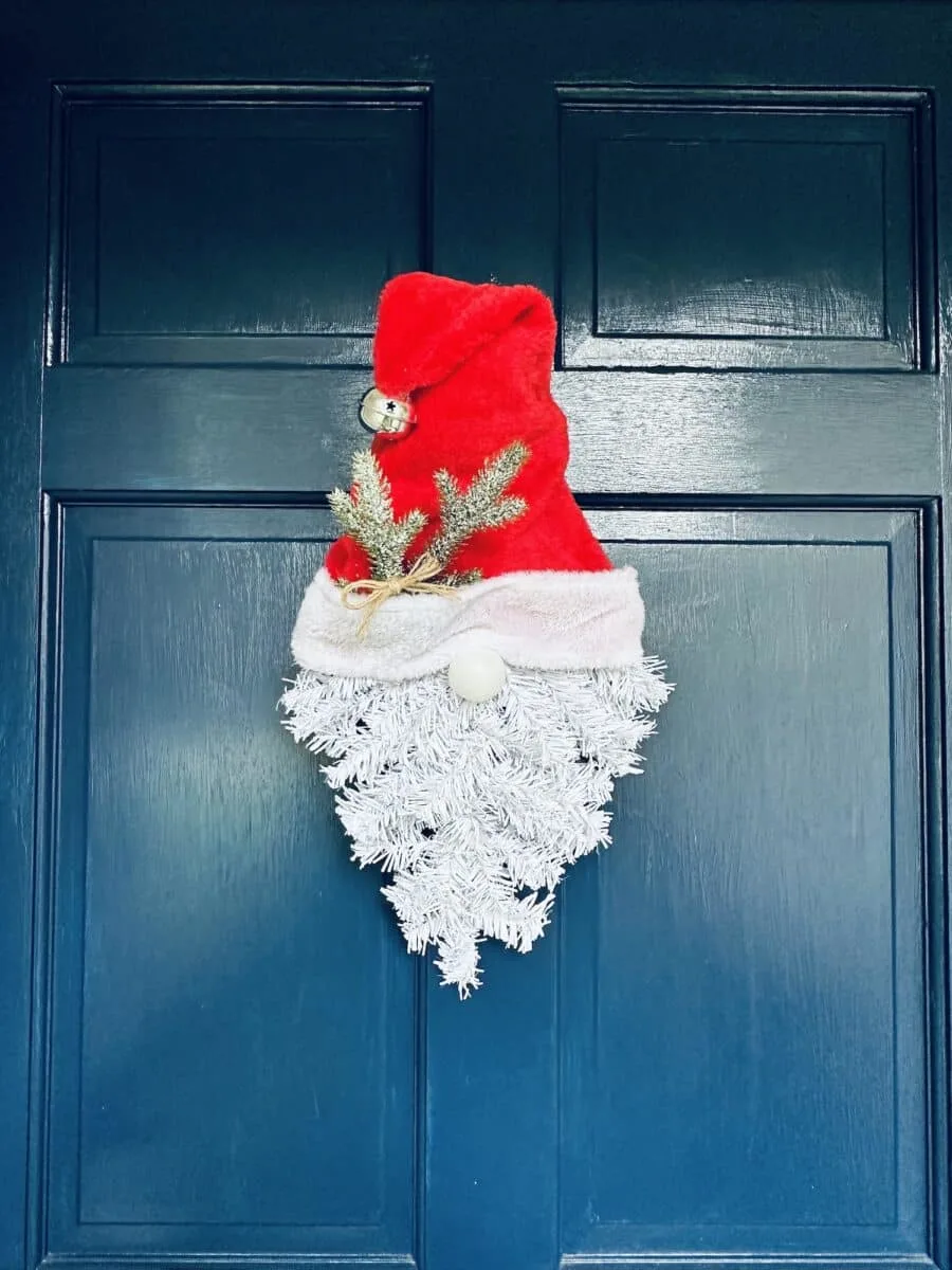 A Santa hat hangs on a blue door.