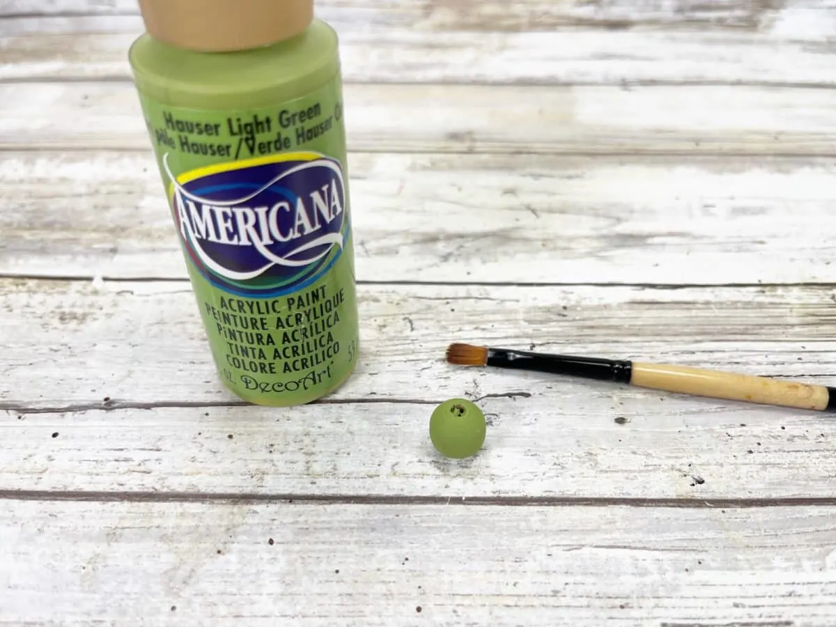 A bottle of green paint and a brush next to it.