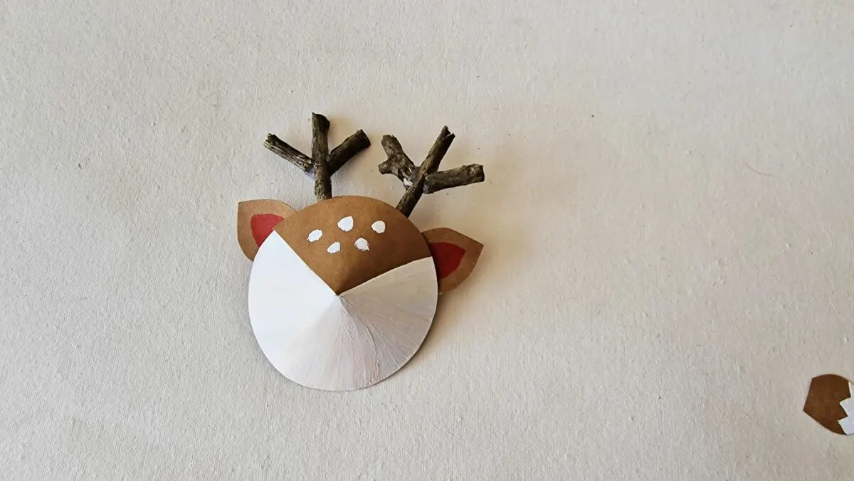 A paper reindeer head hanging on a wall.
