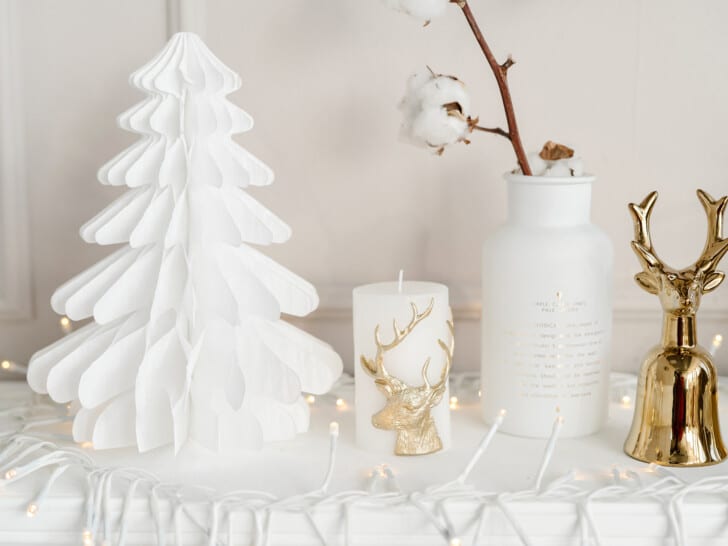 white paper tree on marble table next to gold reindeer decorations