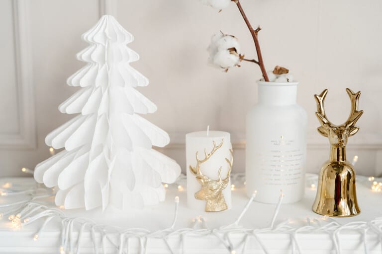 white paper tree on marble table next to gold reindeer decorations