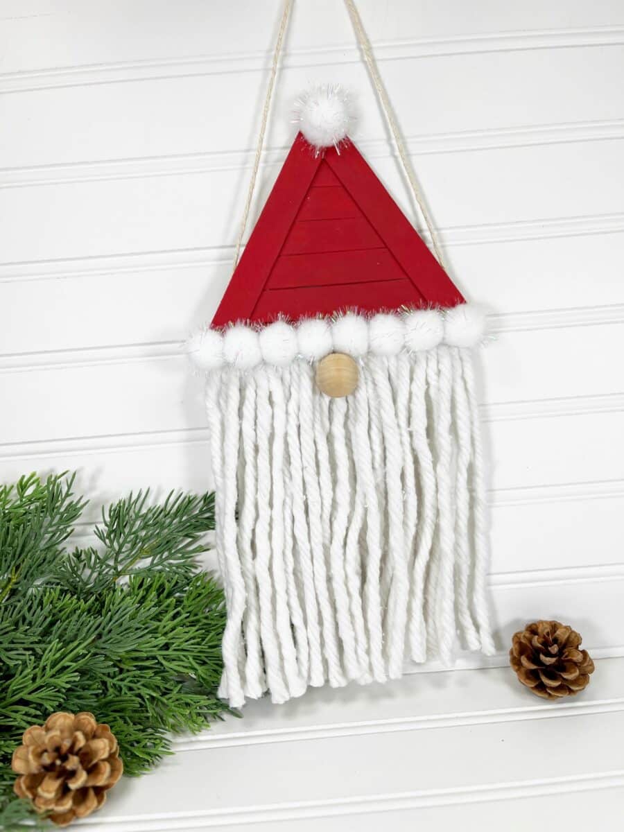 A wooden santa claus hanging on a white wall.