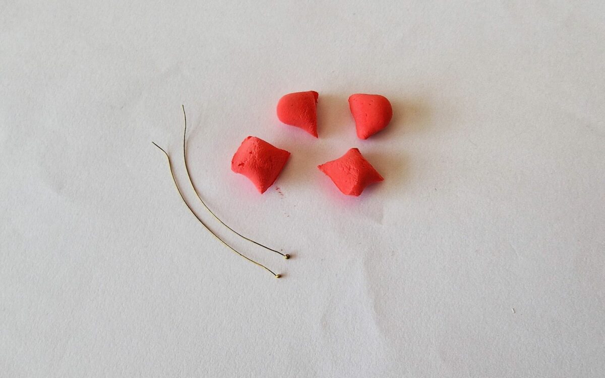 A set of red clay pieces and a pair of scissors on a white surface.