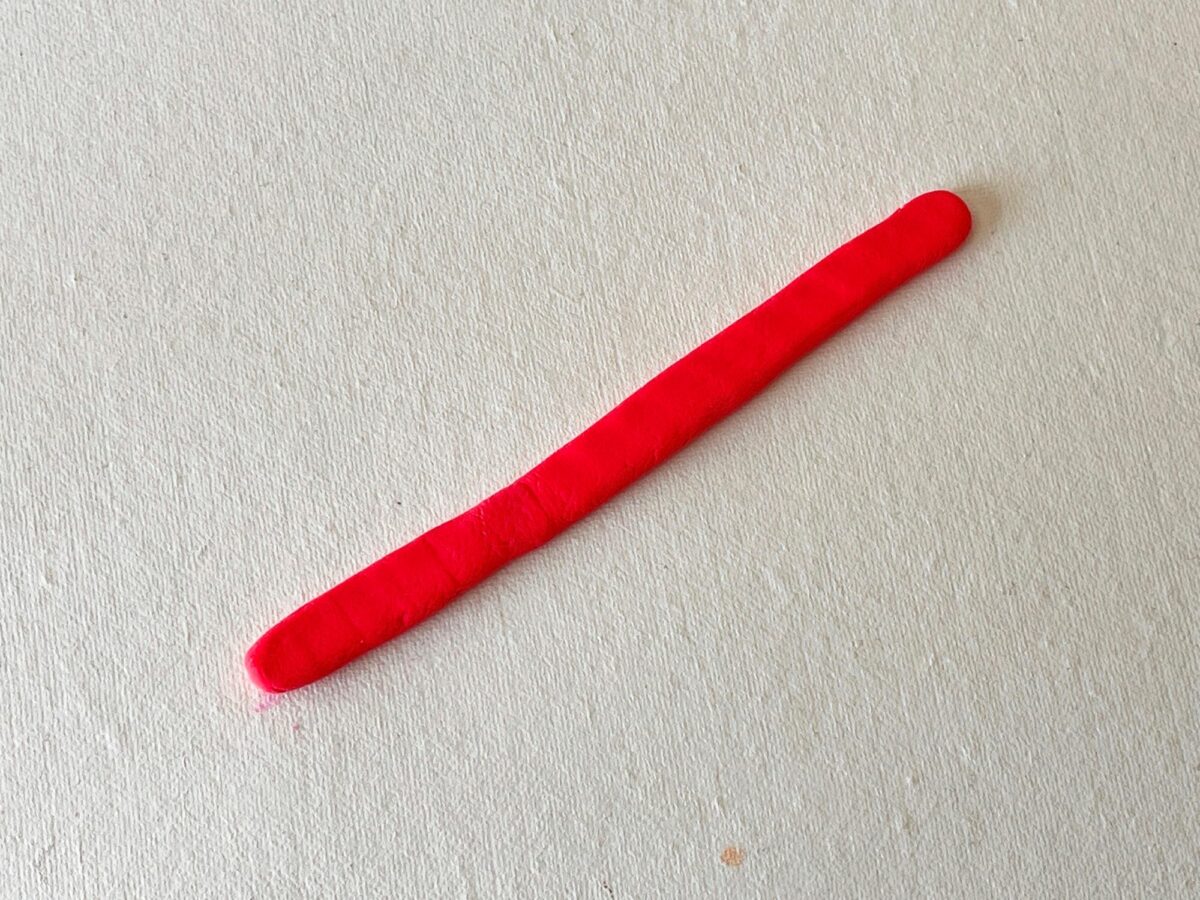 A red plastic stick on a white surface.