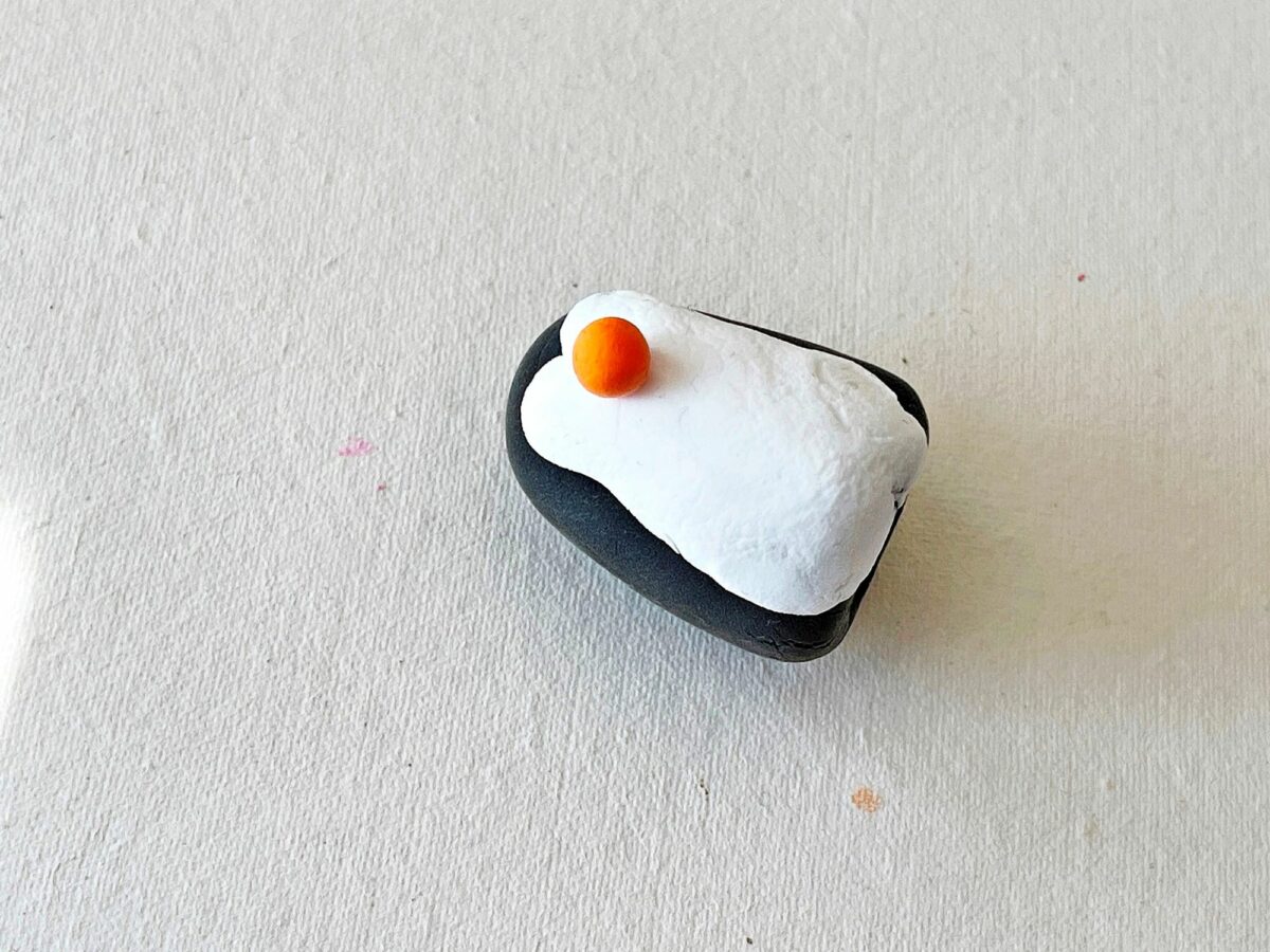 A black and white rock with an orange on it.
