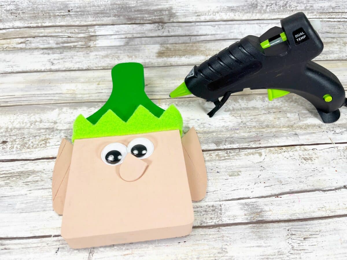 A glue gun with a green head next to it.