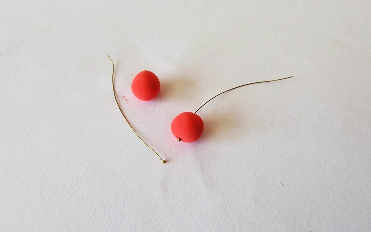 Two red bead earrings on a white surface.
