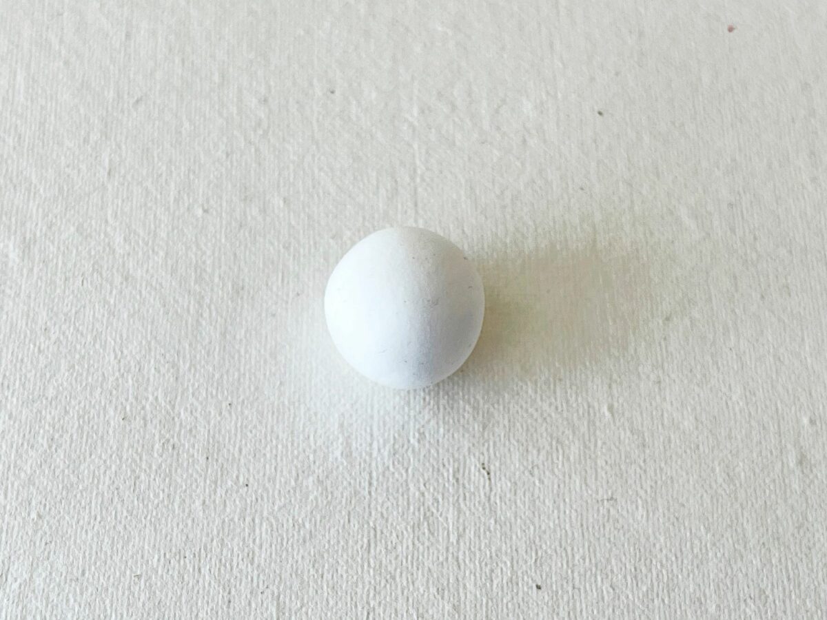 A white egg sitting on a white surface.