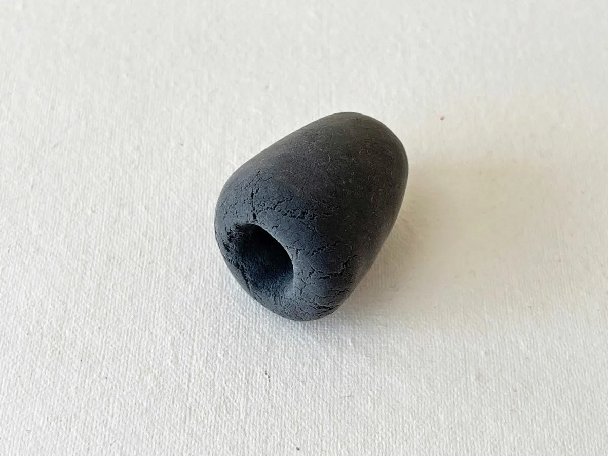 A black bead sitting on a white surface.