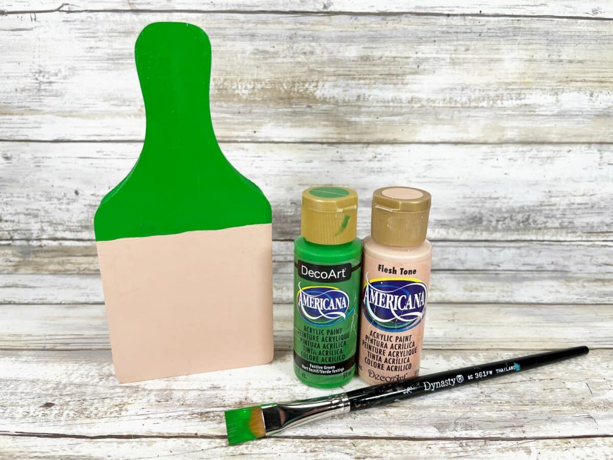 A green paint brush, paints, and a paint brush.