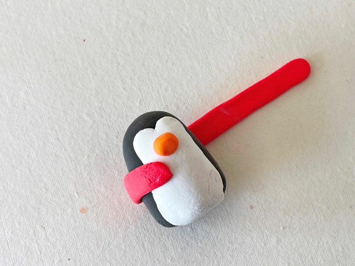 A penguin with a red and black handle on a white surface.