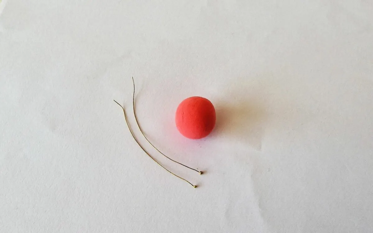 A red ball and a pair of scissors on a white surface.