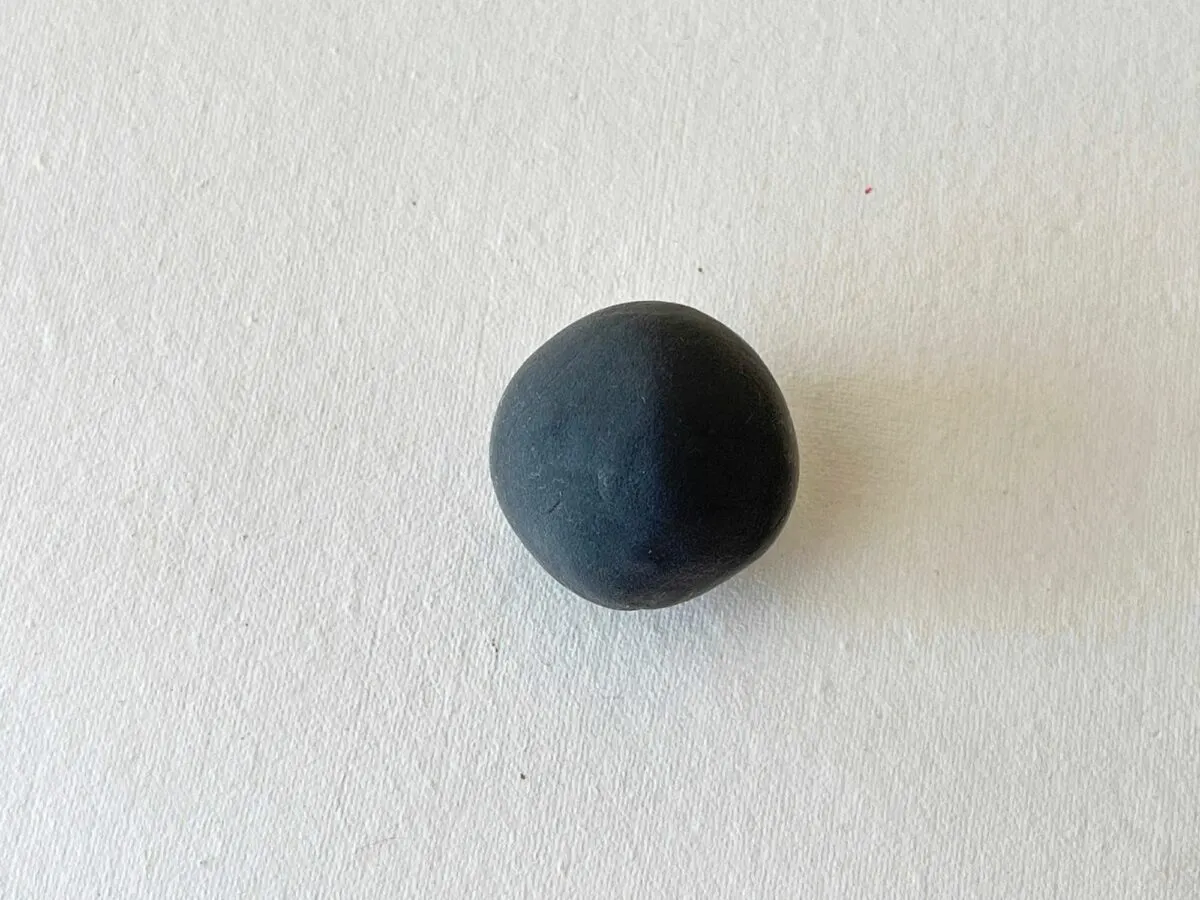 A black ball sitting on a white surface.