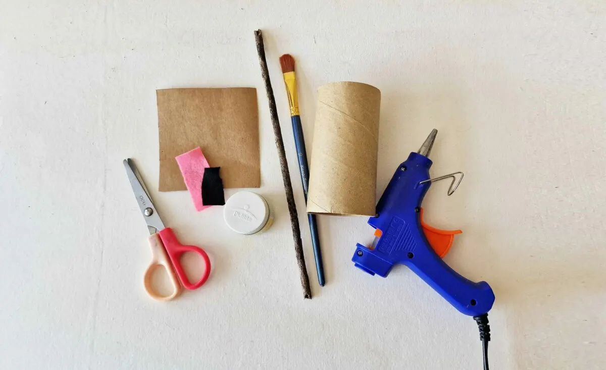 A group of scissors, glue, and paper are laid out on a white surface.