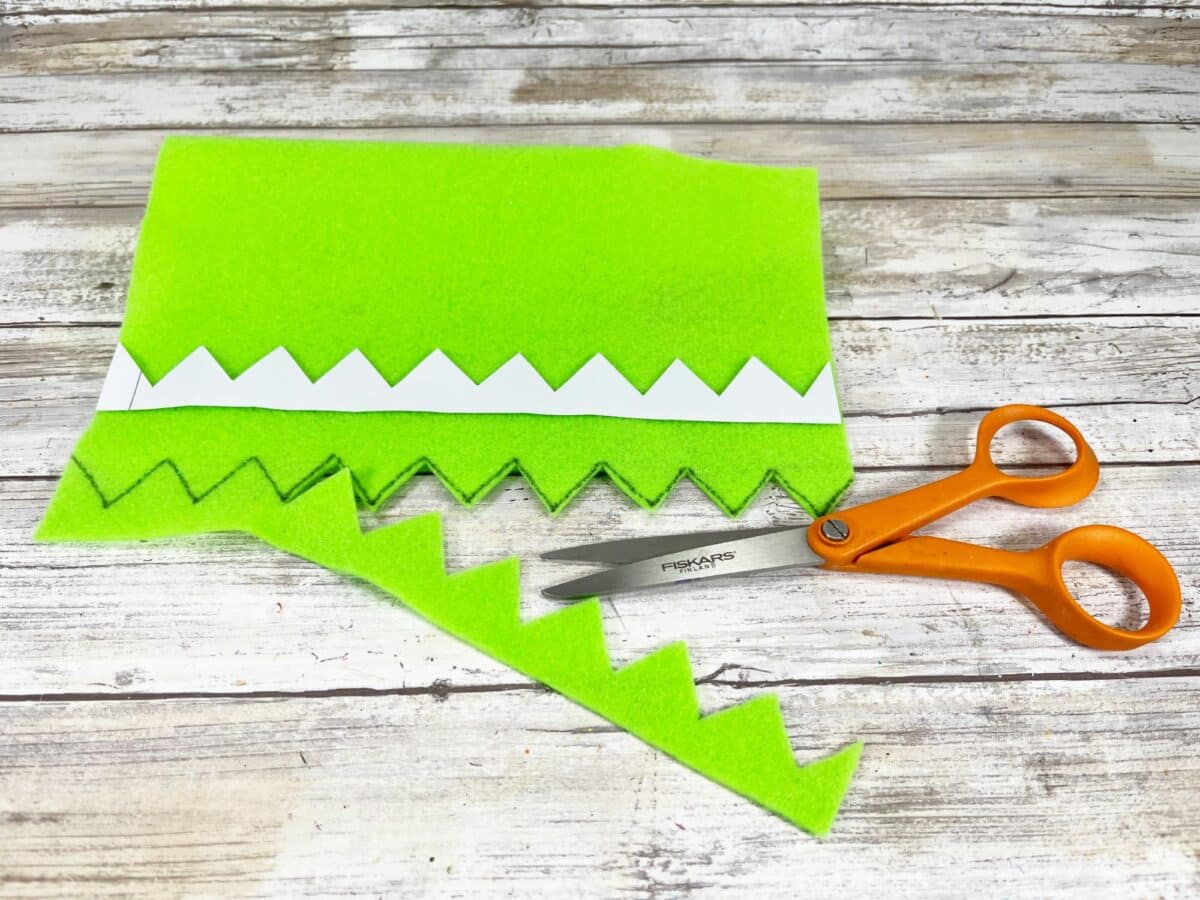 A pair of scissors next to a piece of green felt.
