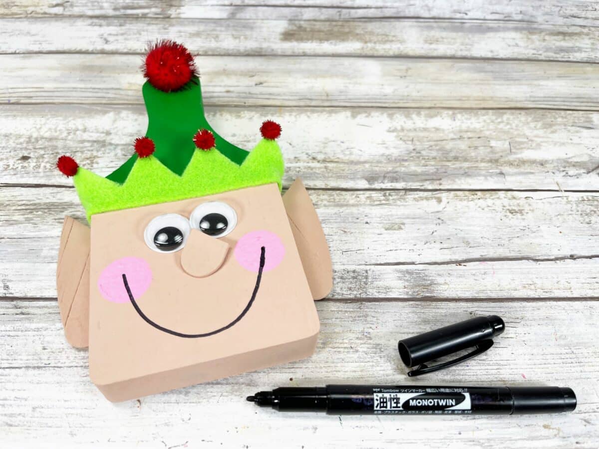 A christmas elf box with a marker and a green elf hat.