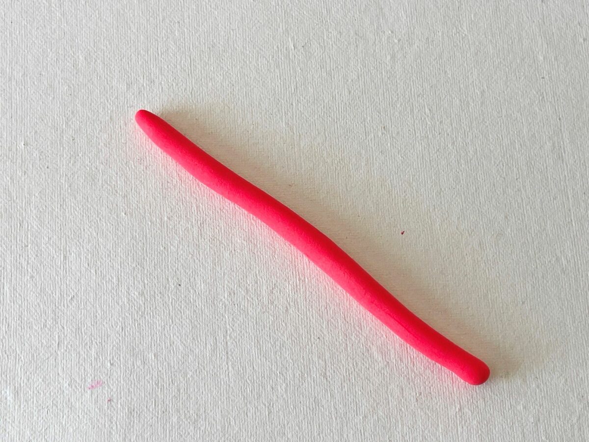 A pink plastic syringe lying on top of a white surface.