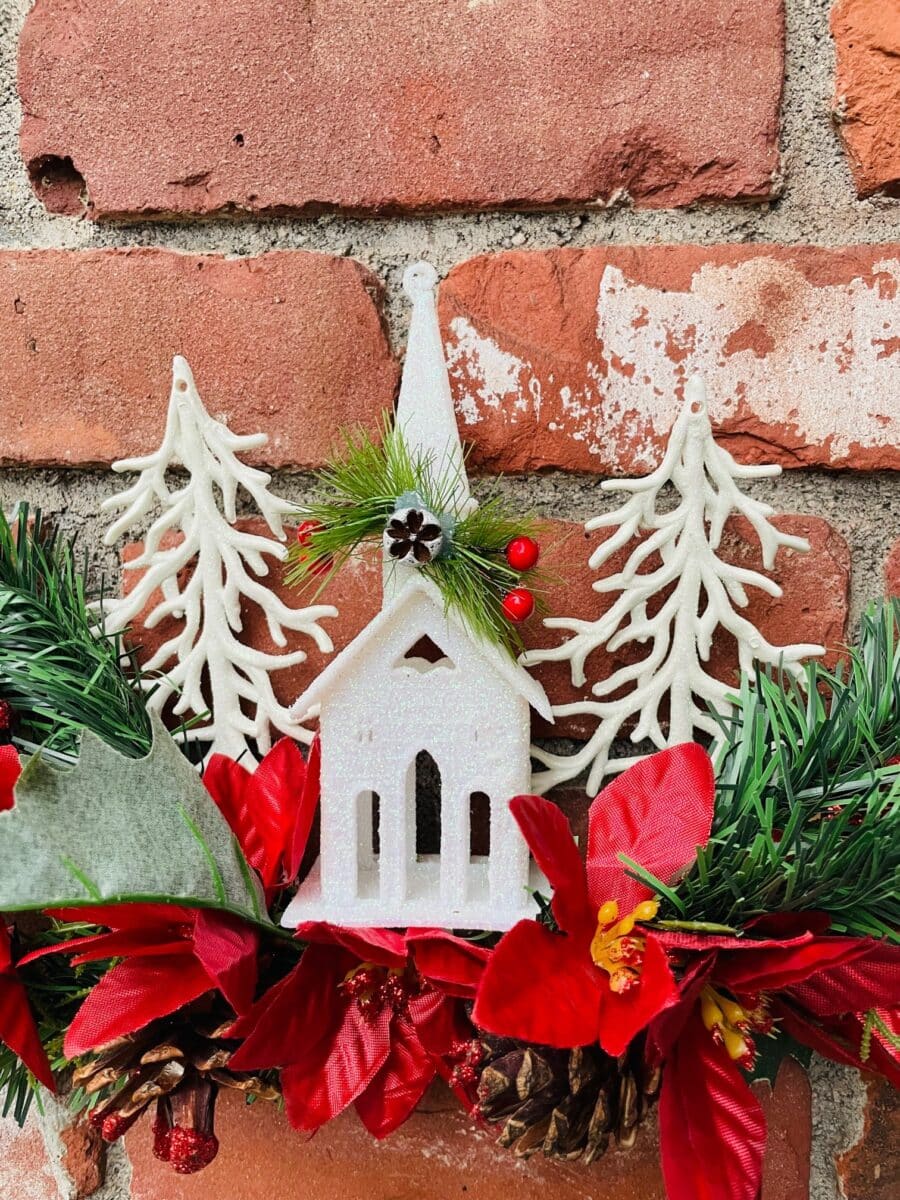 A christmas wreath with a church on a brick wall.