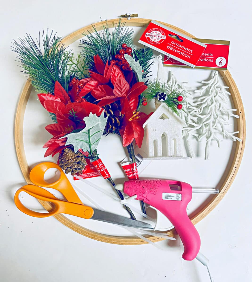 A hoop with christmas decorations and scissors on it.