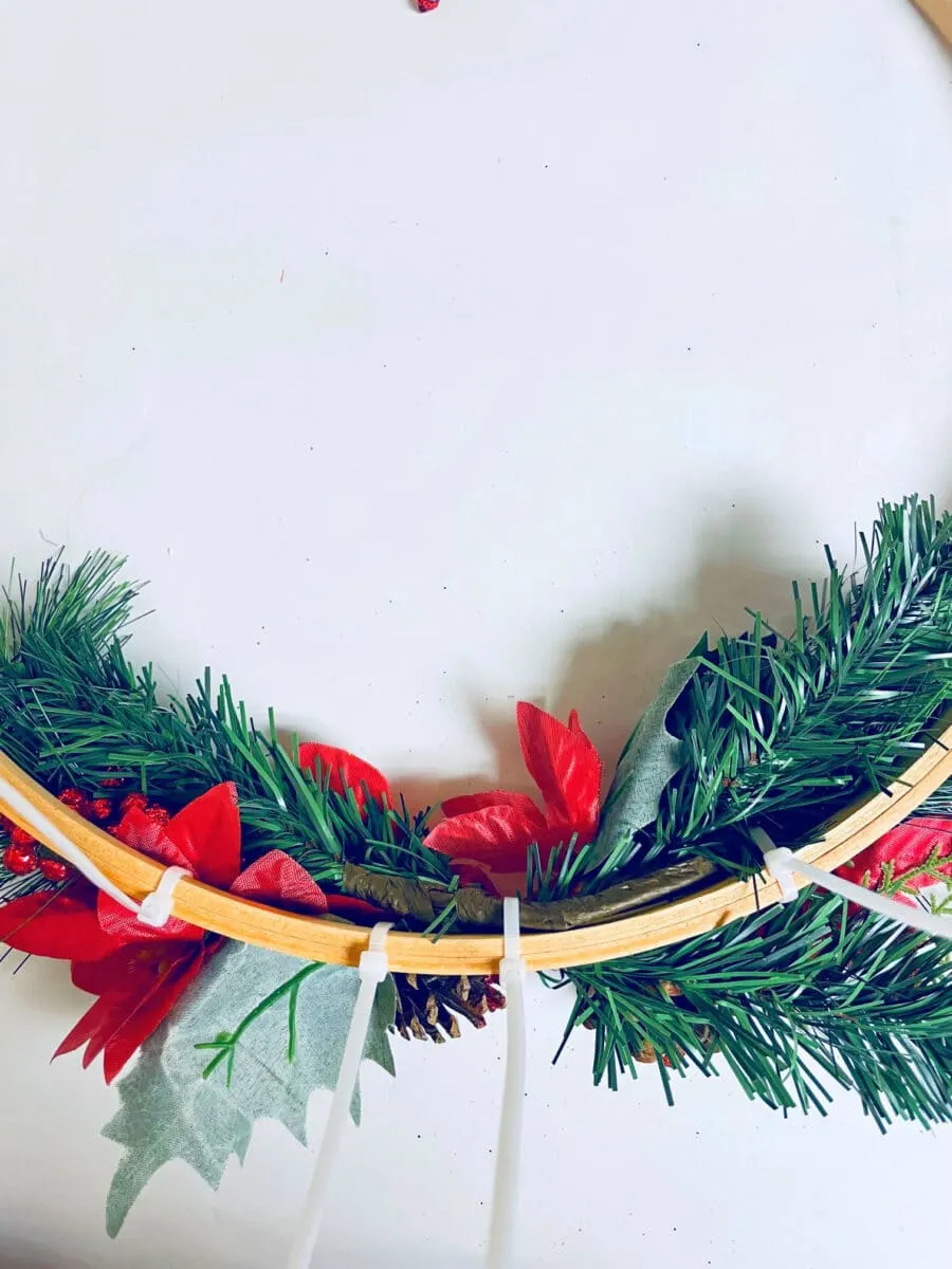 A wooden hoop with red and green leaves and pine cones.