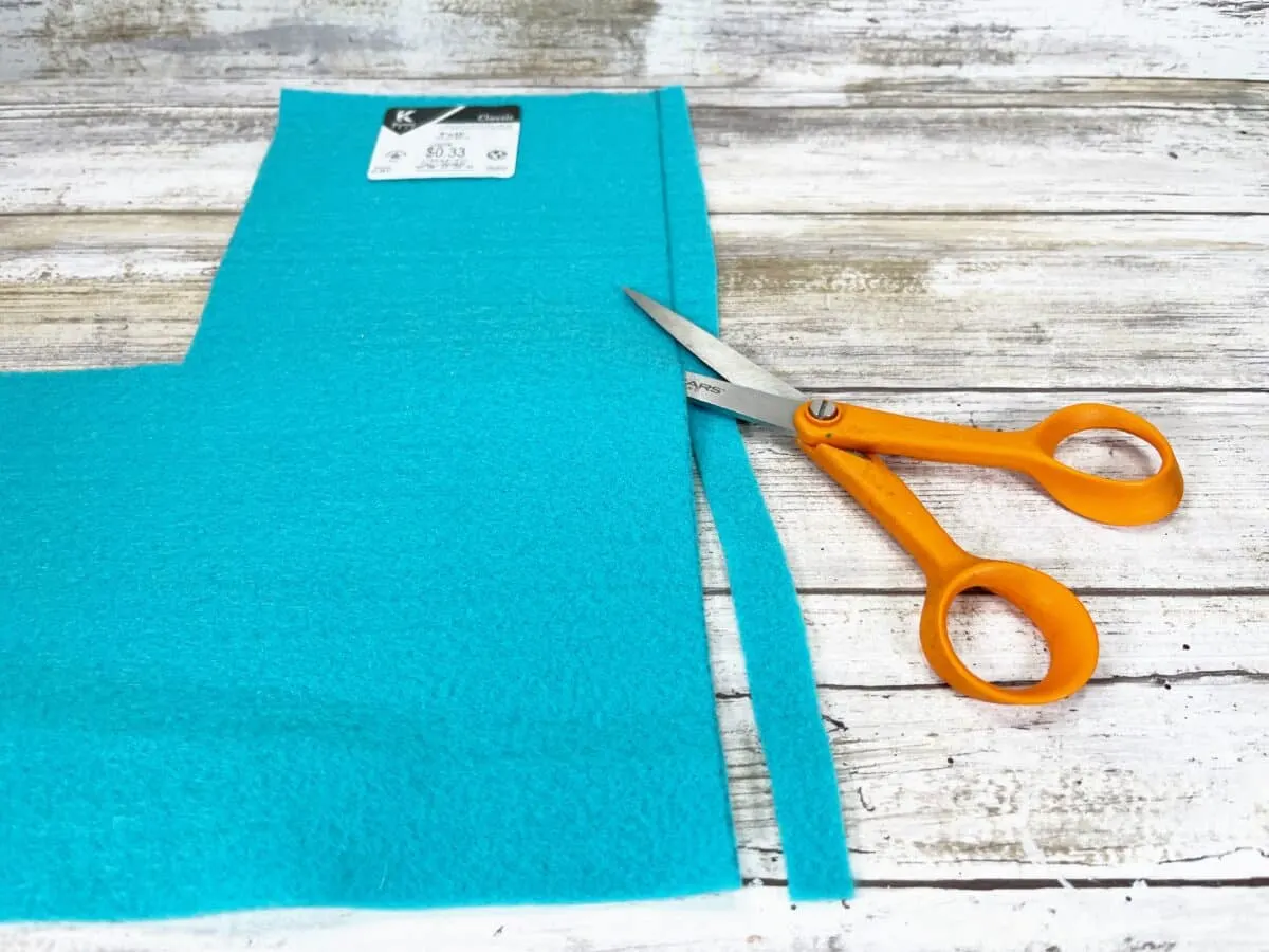 A pair of scissors next to a piece of turquoise fabric.