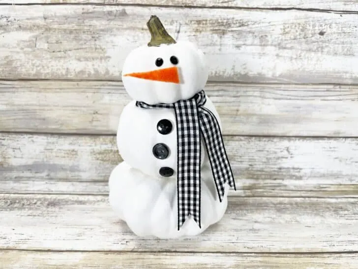 A snowman made out of white pumpkins and a plaid scarf.