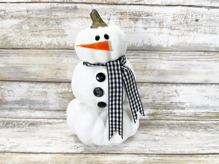 A snowman made out of white pumpkins and a plaid scarf.