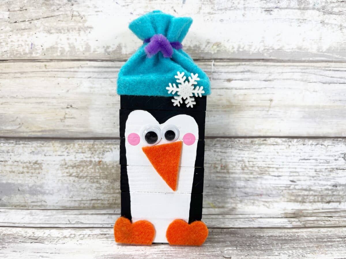 A felt penguin on a wooden background.