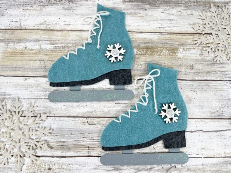 Two blue felt ice skates on a wooden background.