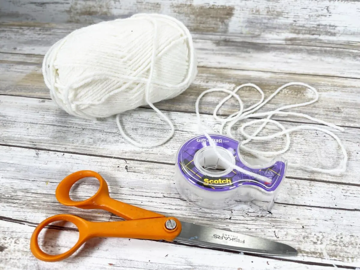 A pair of scissors and a ball of yarn on a wooden table.