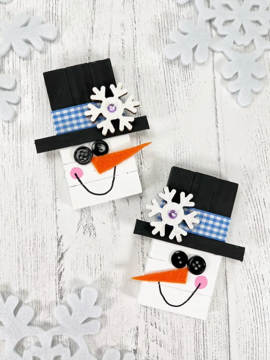 Two wooden snowmen with hats and snowflakes.