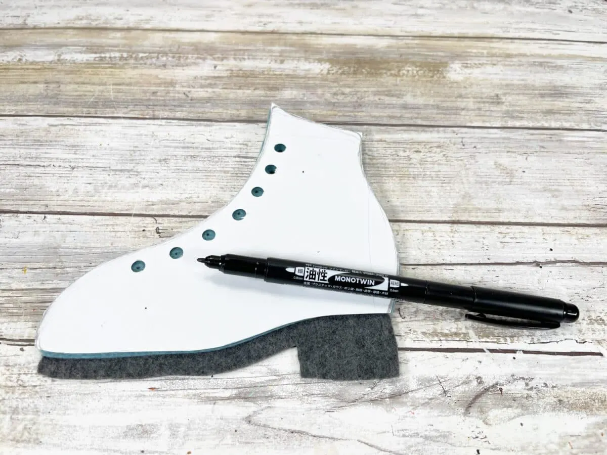 A pair of ice skates and a pen on a wooden table.