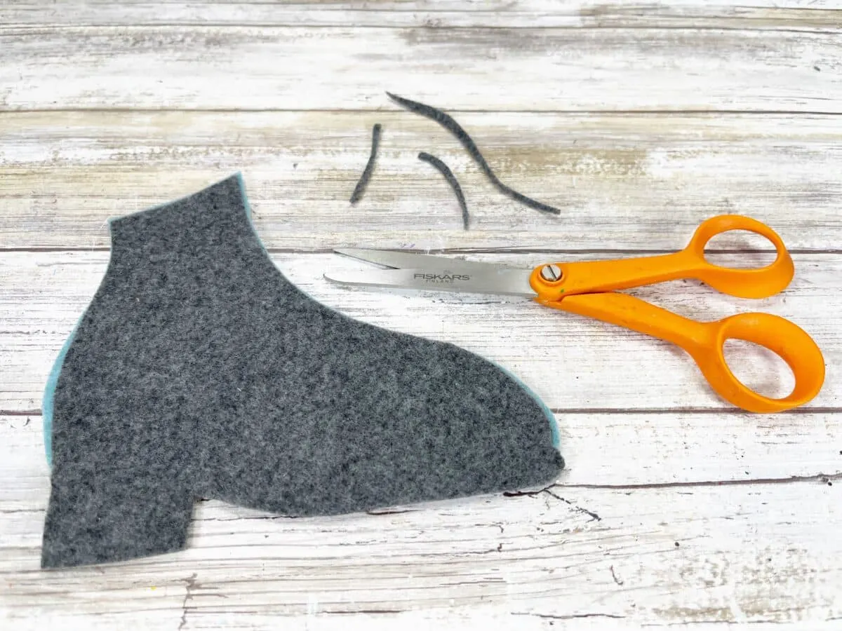 A pair of scissors next to a pair of felt shoes.