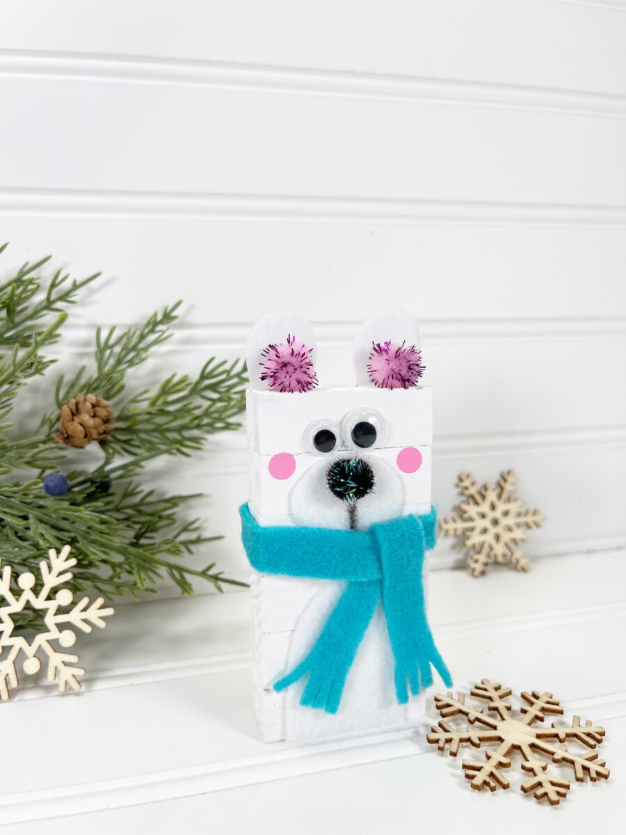 A polar bear gift box with a blue scarf and pinecones.