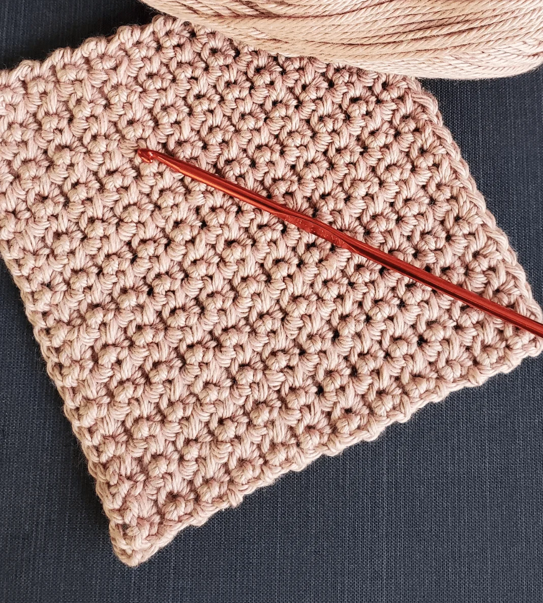 A beginner crochet kit featuring a crocheted square, crochet hook, and yarn.