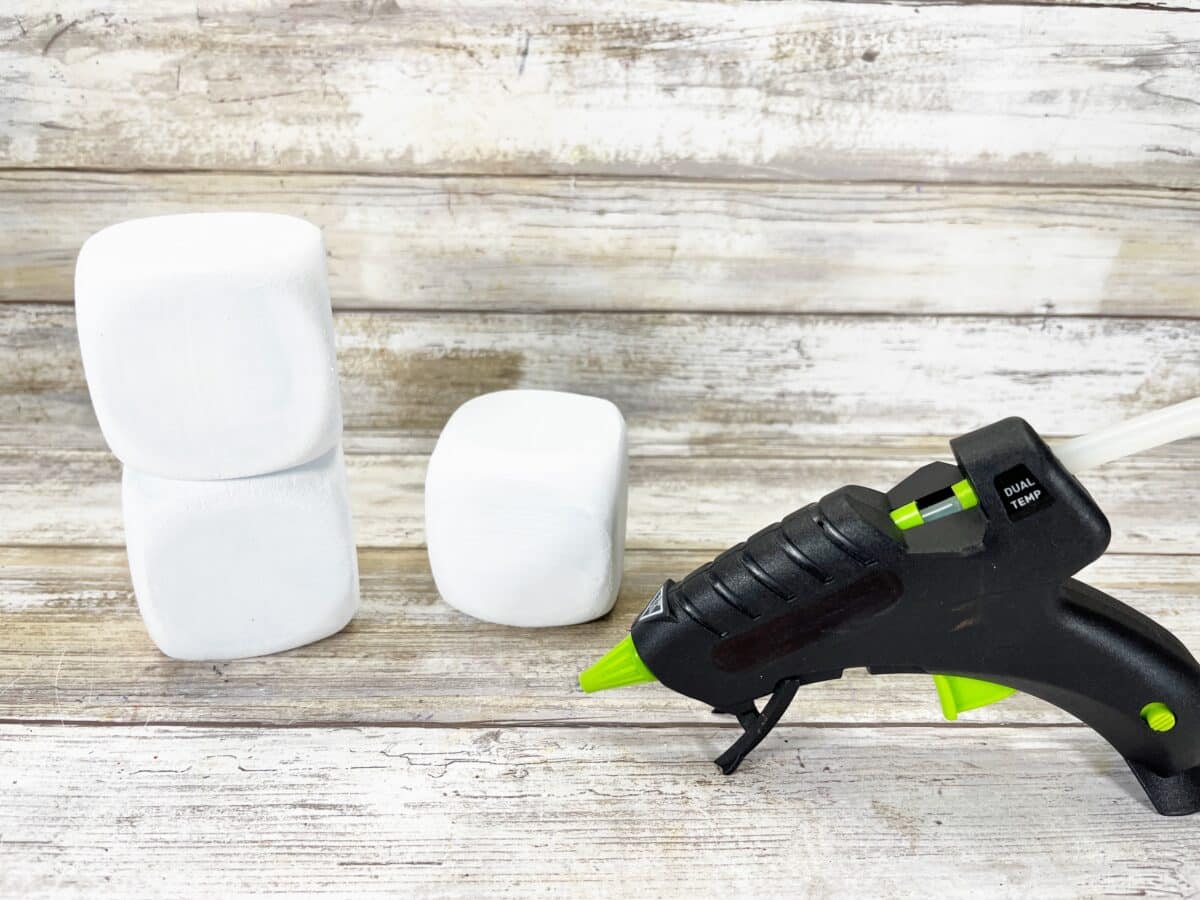 A glue gun next to a set of white foam cubes.