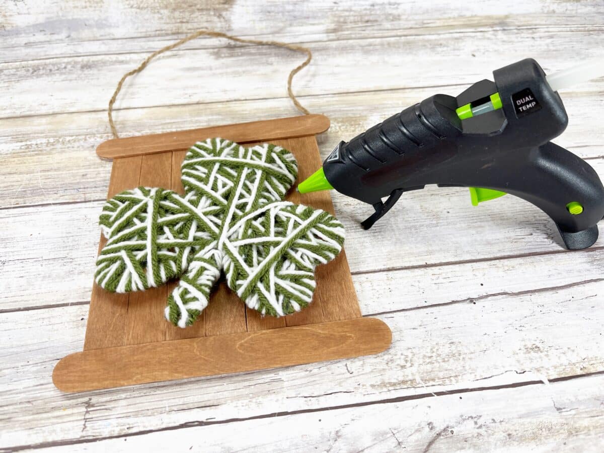 Shamrock cookies with a glue gun on a wooden board.