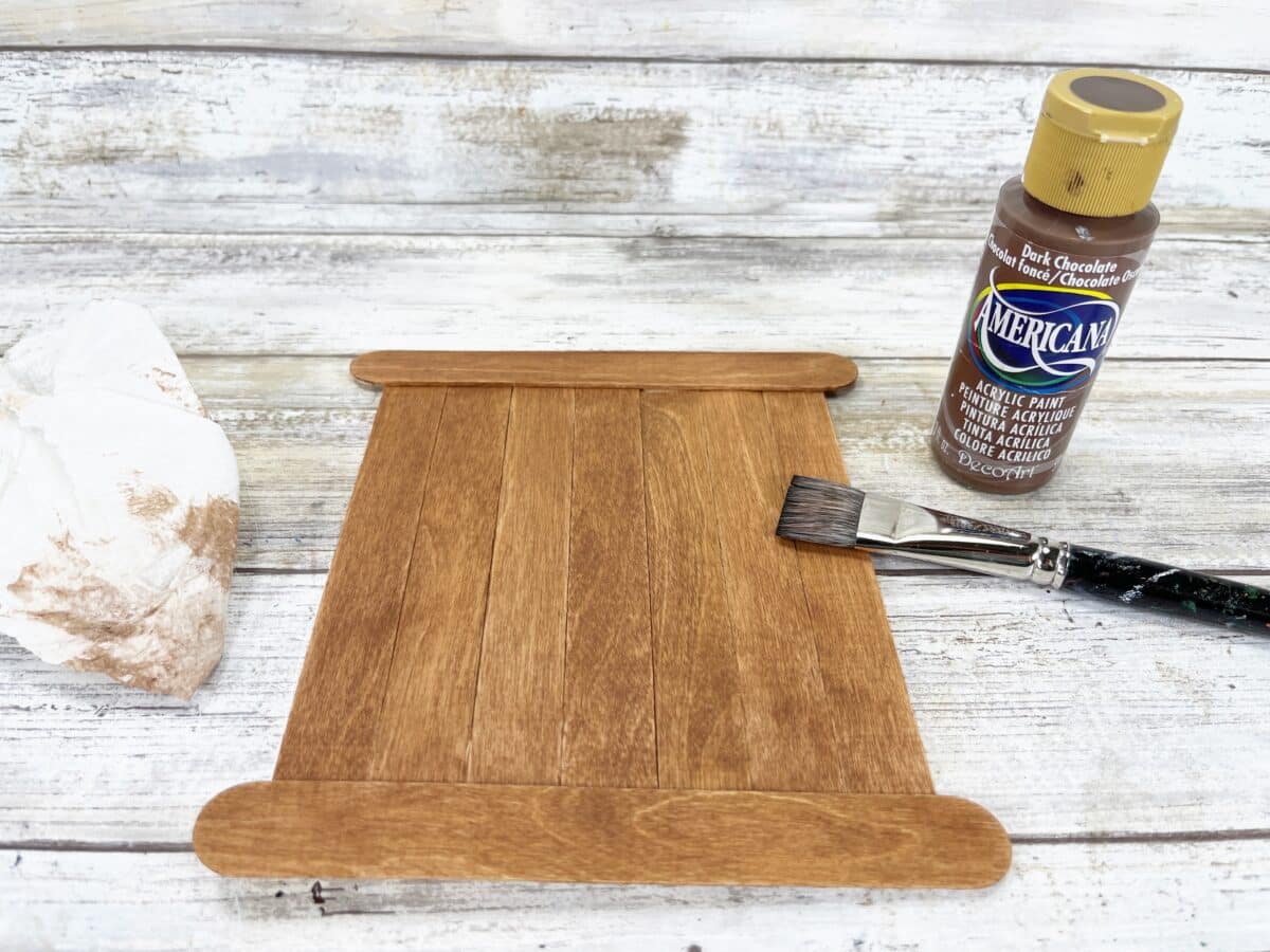 A wooden board with paint and a paint brush.