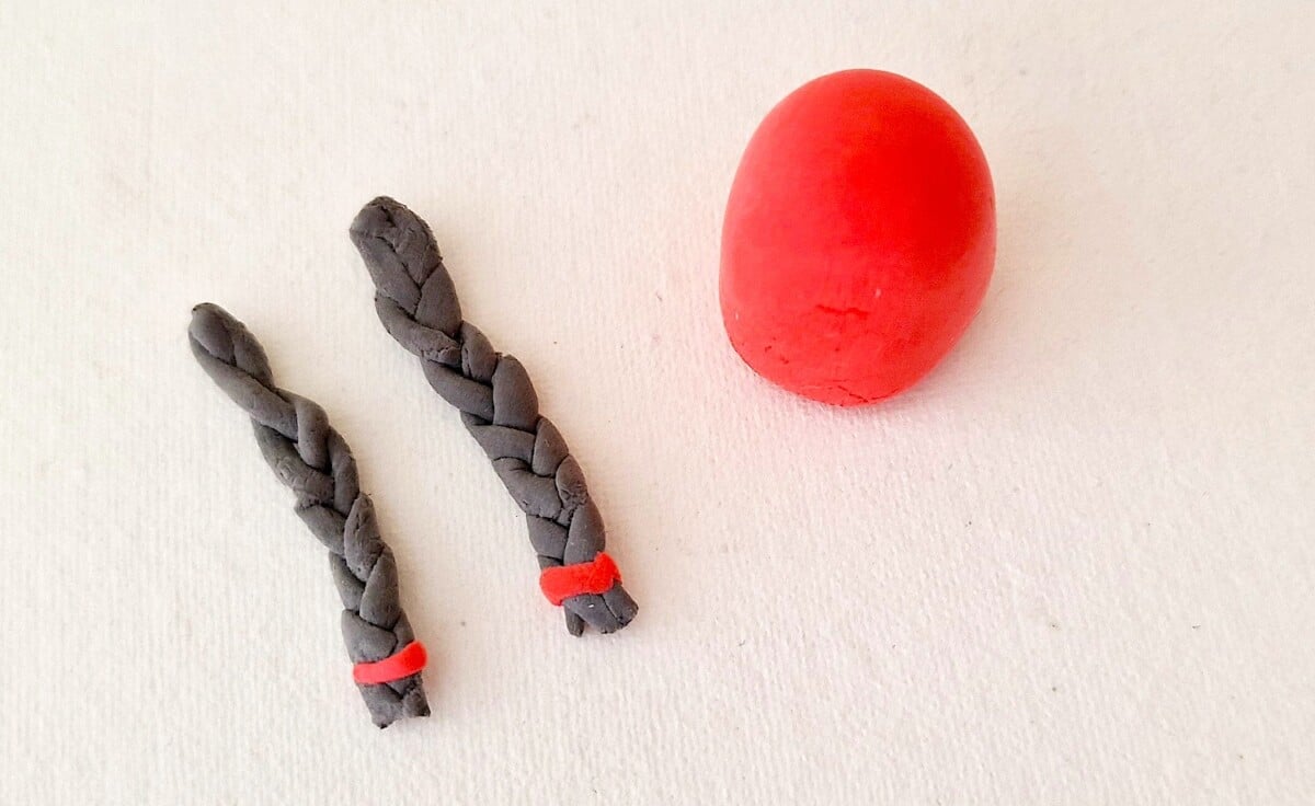 Clay Gnome Step 7 A red and black braided egg next to a red ball.