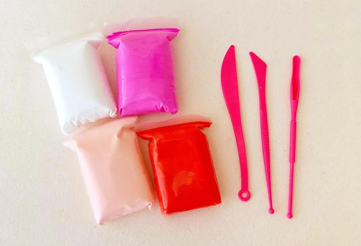 A package of pink and red paint and a pair of scissors to make a Clay Gnome.