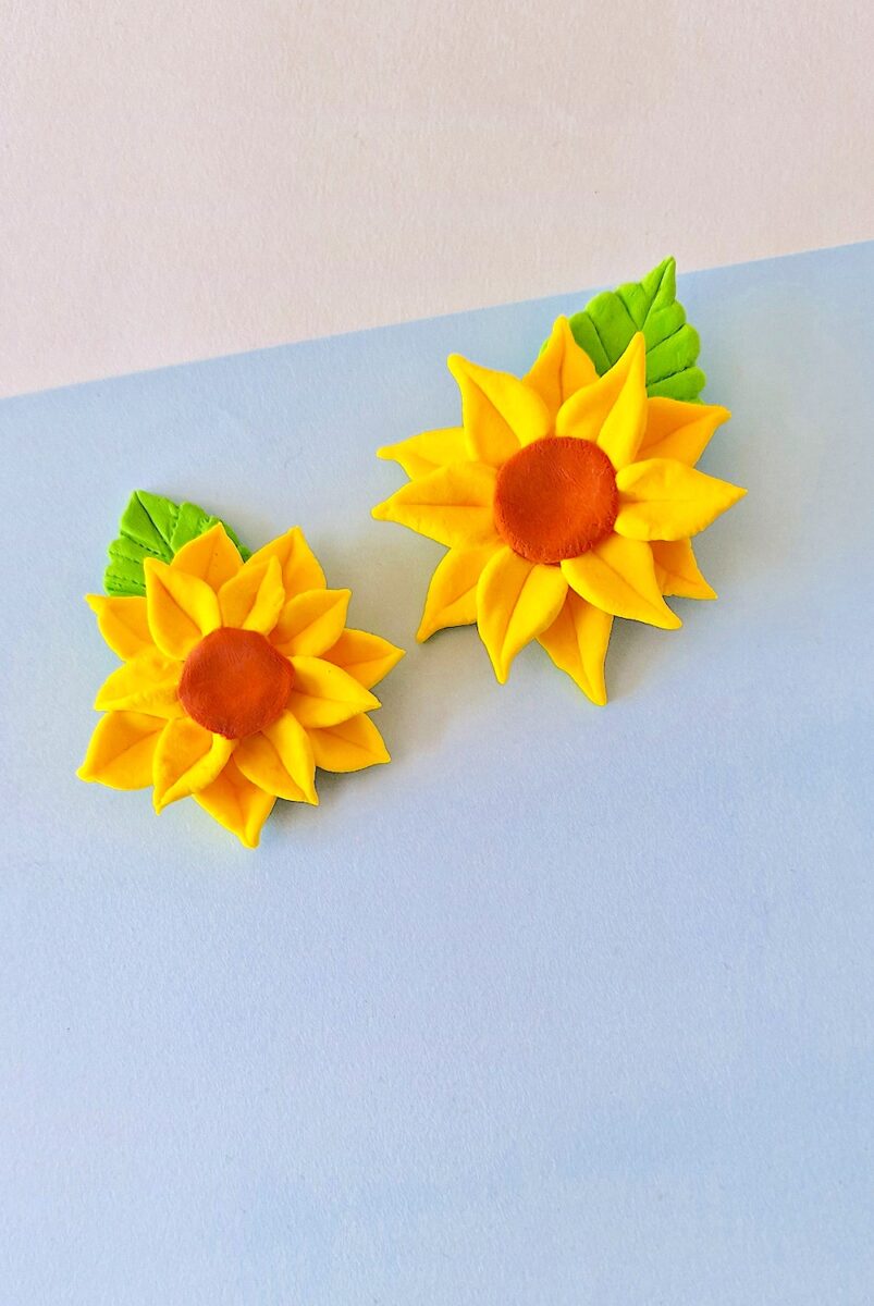 Clay Sunflower with red center and green leaf on blue background