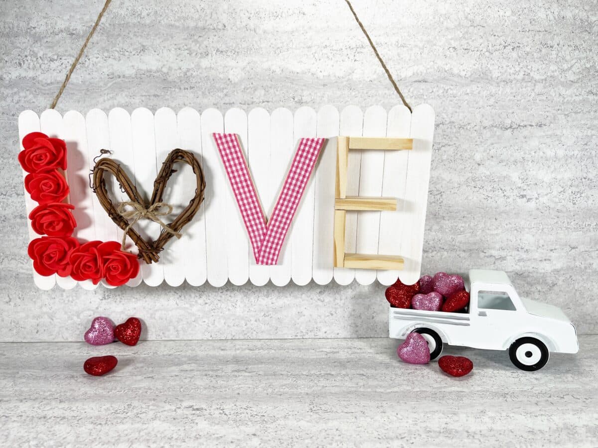 A valentine's day sign with a truck and roses hanging from it.