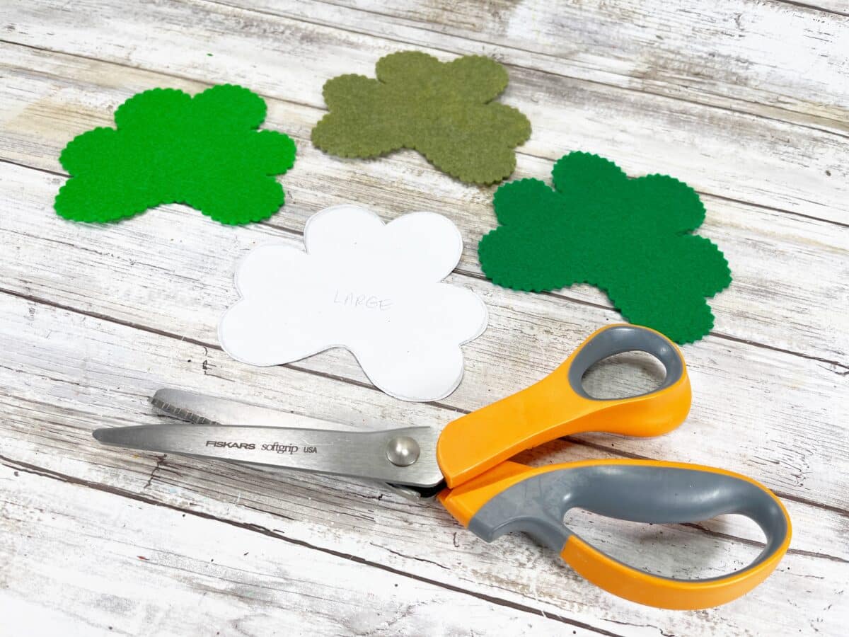 A pair of scissors with shamrocks and shamrocks on a wooden table.