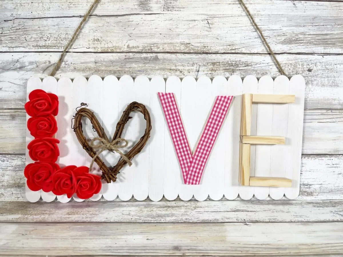 A wooden sign with the word love hanging on a wooden wall.