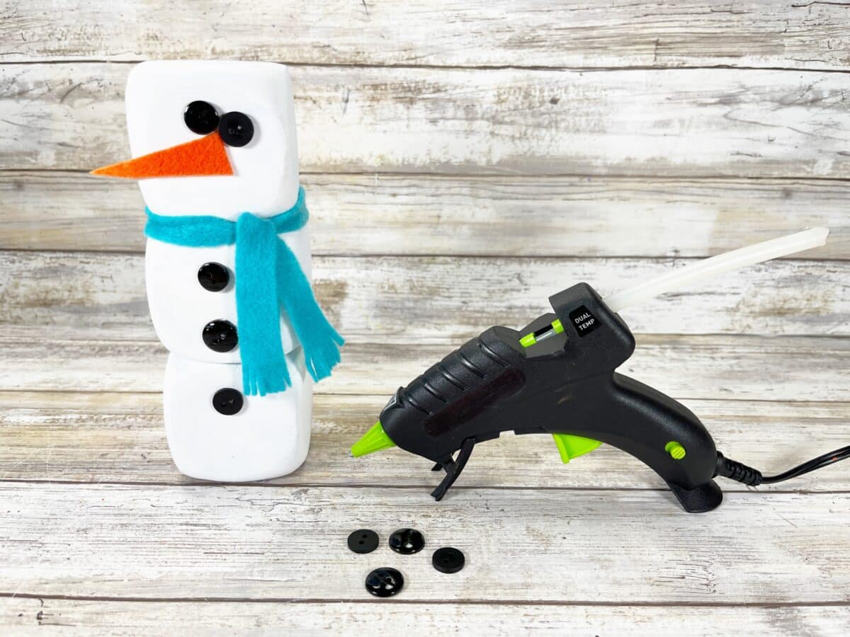 A snowman with a glue gun next to it.