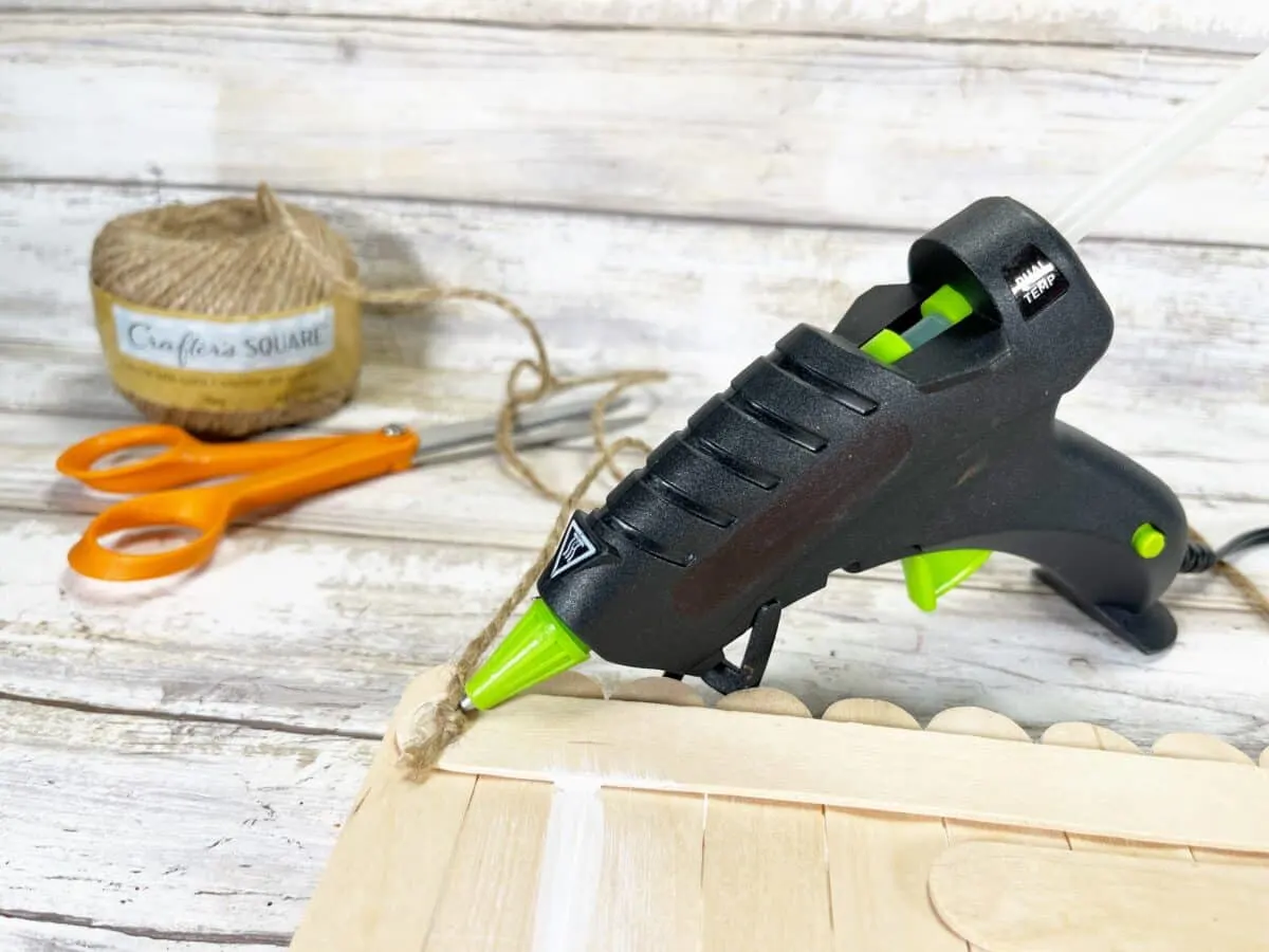 A black and green glue gun on a wooden table.